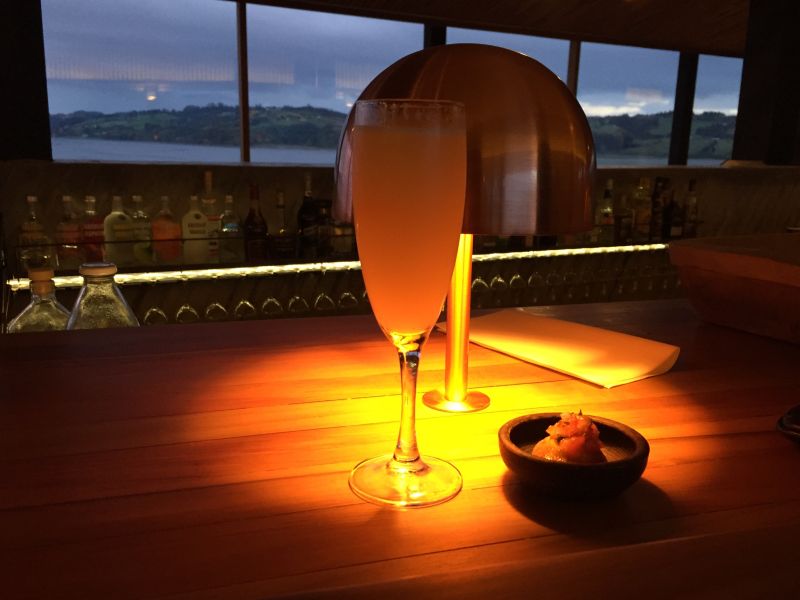 Pisco sour com aperitivo de batatas no bar do Tierra Chiloé